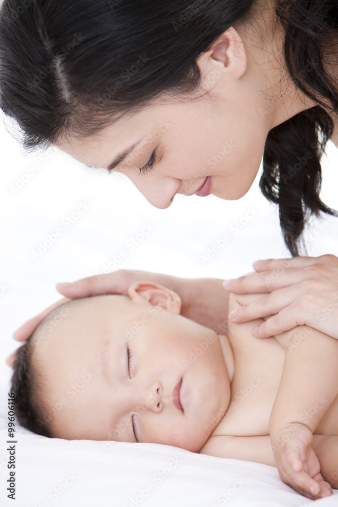 母亲温柔地抚摸熟睡的婴儿