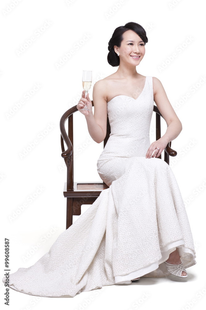 优雅的年轻女子坐在中国明代木扶手椅上，手里拿着香槟长笛