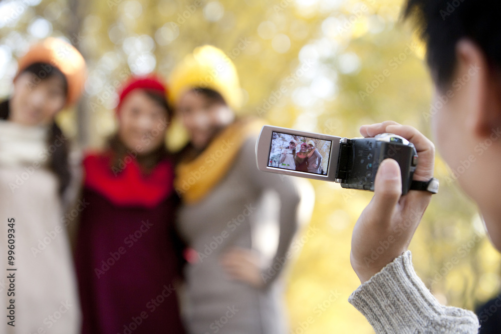 年轻人用家用摄像机拍摄3个朋友