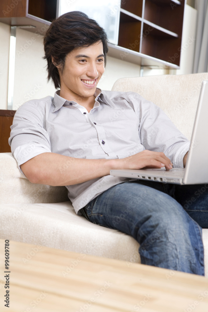 Asian man on sofa with laptop