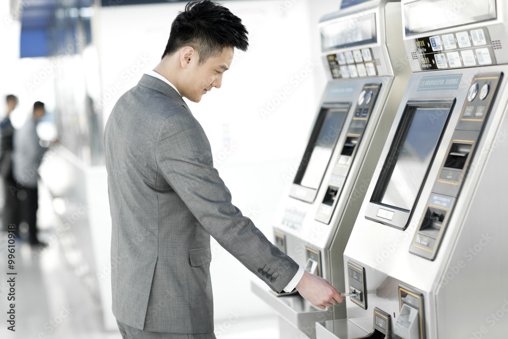 Young businessman using automatic ticket machine at subway station