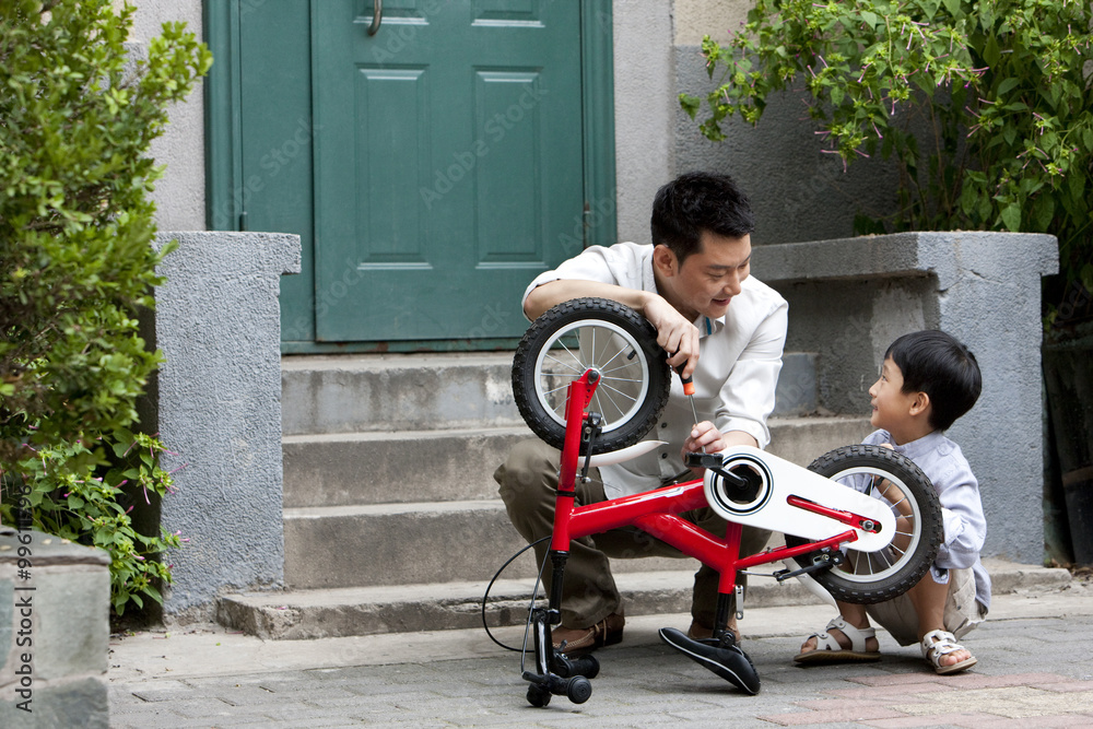 年轻的中国父子修自行车