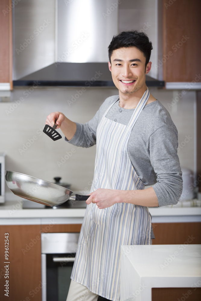 Happy young man cooking in kitchen