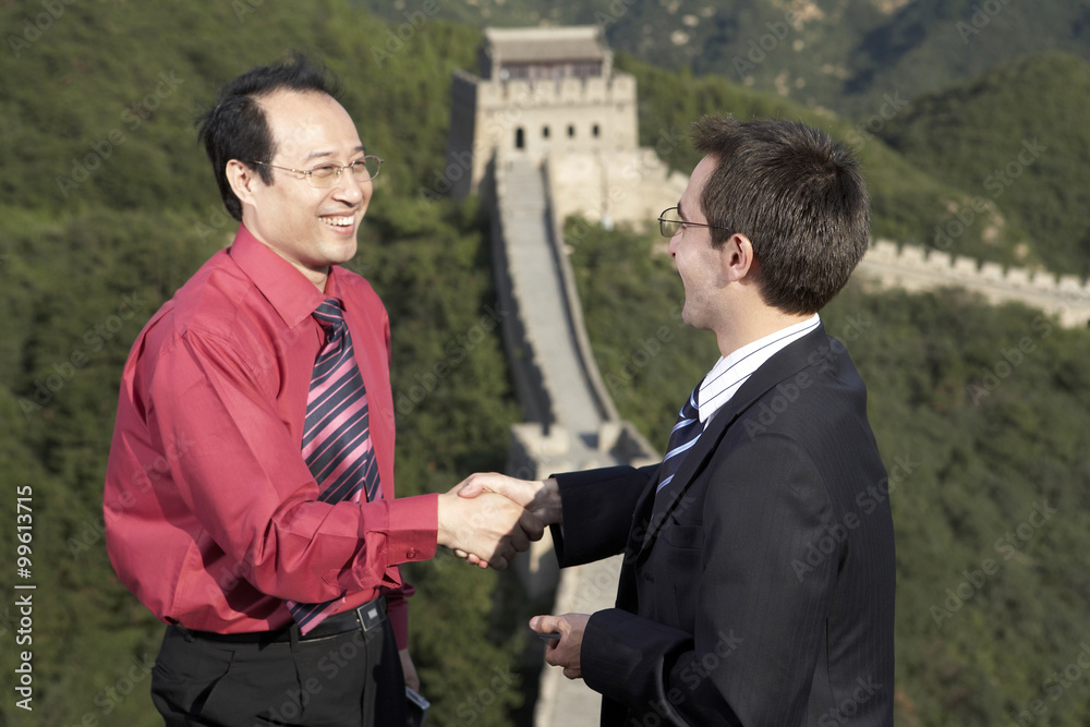 Businessmen Standing On The Great Wall Of China, Shaking Hands