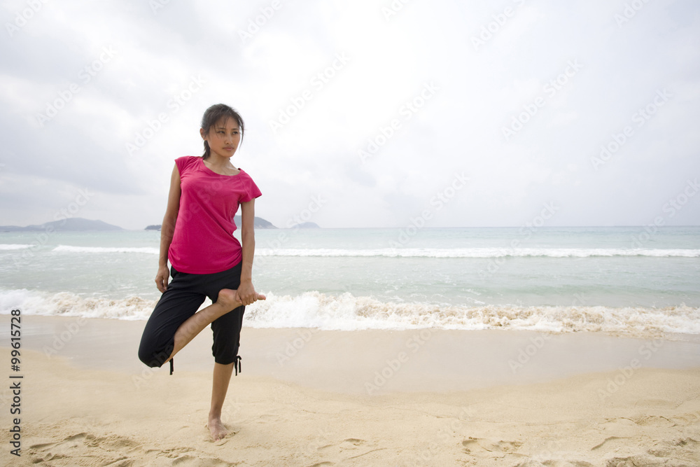 年轻的女人在海边伸展身体