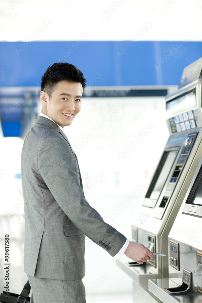 年轻商人在地铁站使用自动售票机