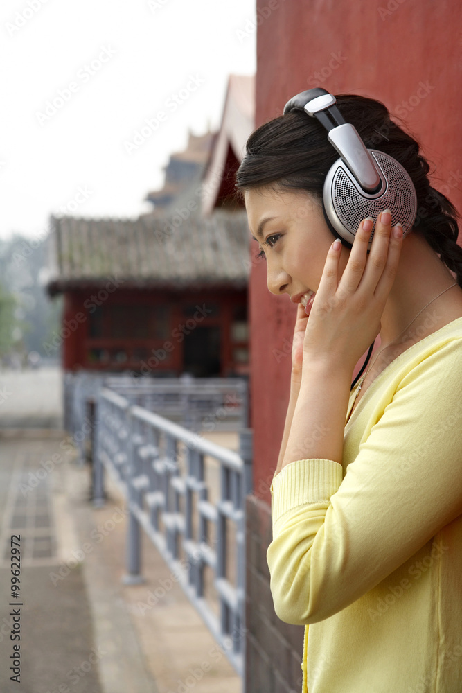 Young Woman Wearing Headphones Standing Outside The Forbidden City In Beijing