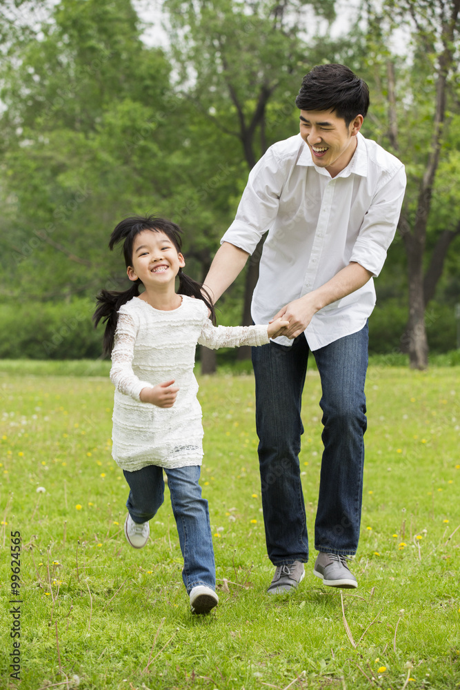 幸福的父女牵着手在草地上奔跑