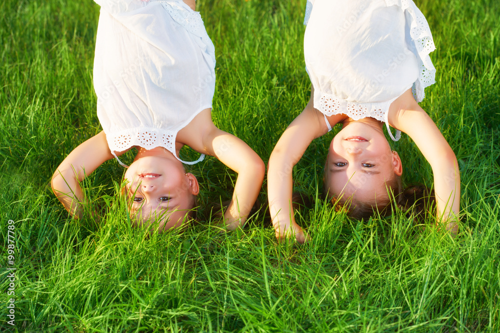 happy children twins sister upside down in summer