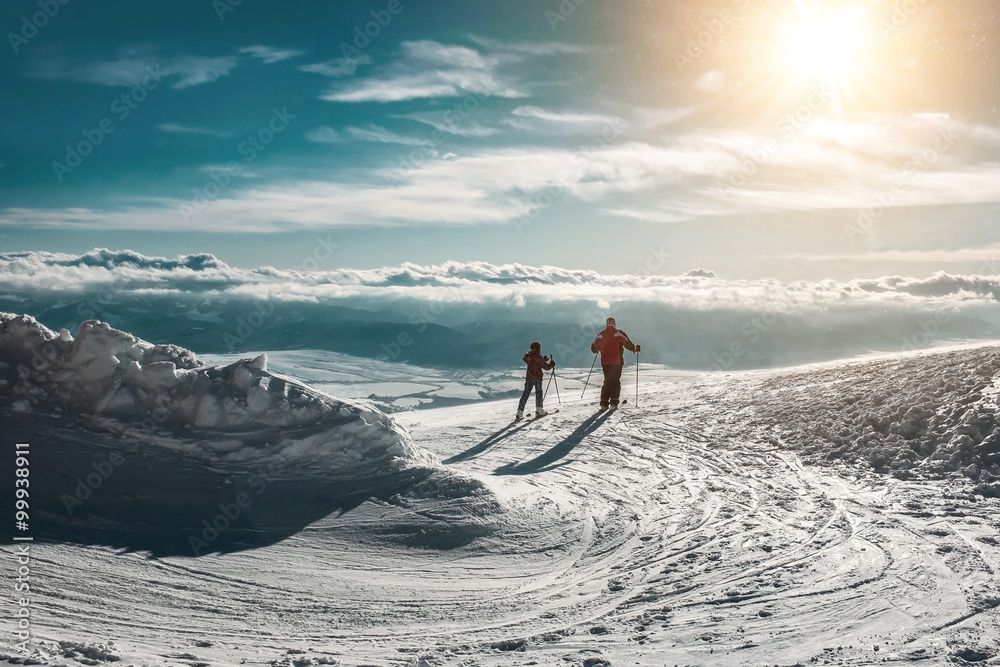 阳光明媚的日子里，两名滑雪者在山顶上。