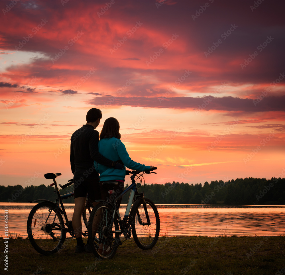 Couple with Bicycles Watching Sunset at River