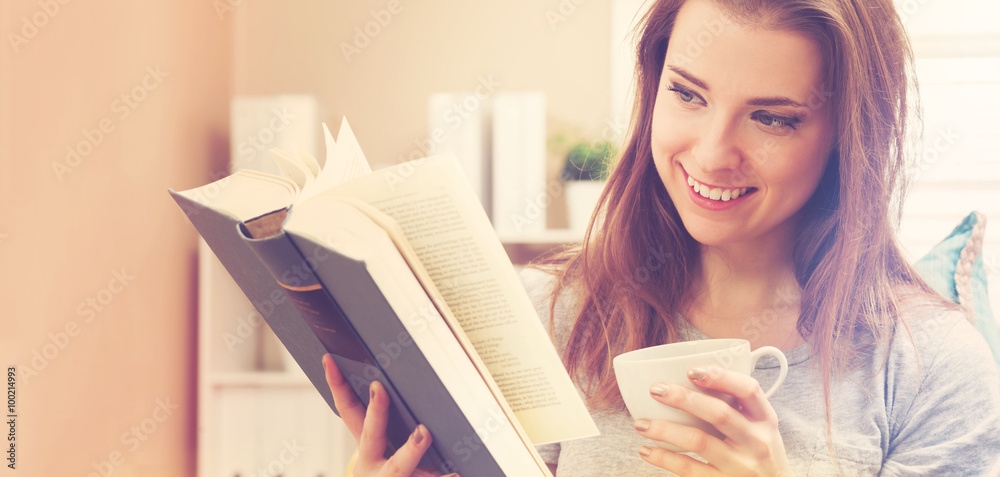 Happy young woman reading a book