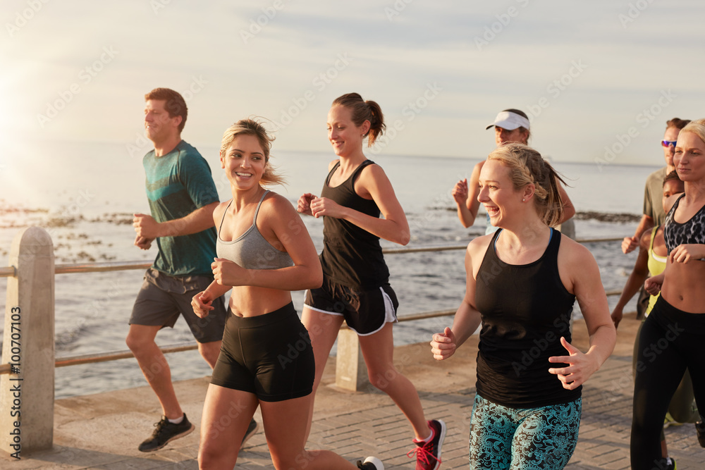 Healthy young people running together on seaside promenade