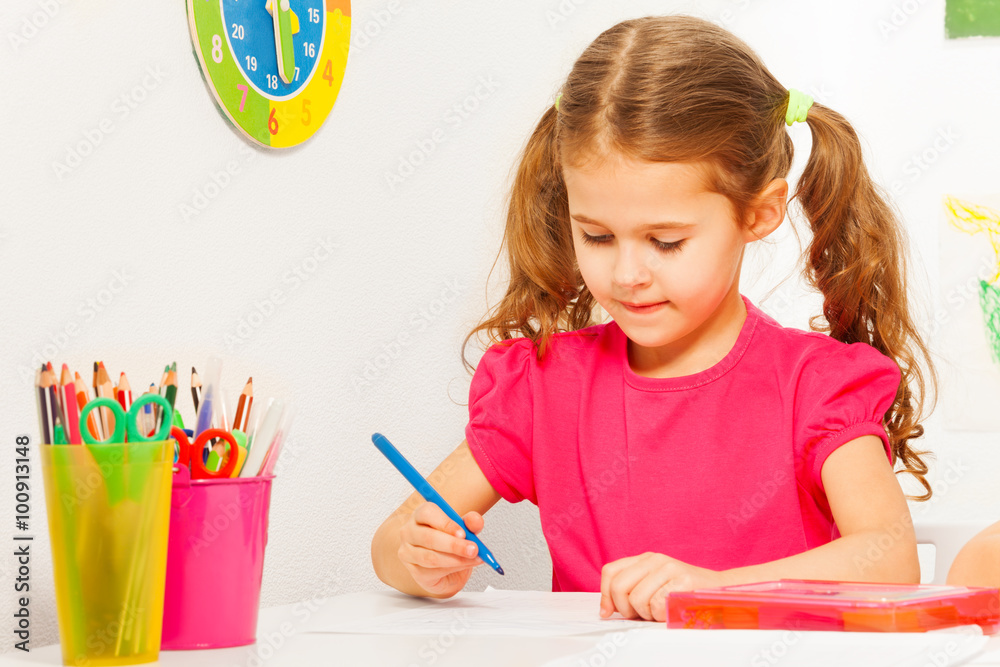 One schoolgirl writing with blue pen at the desk