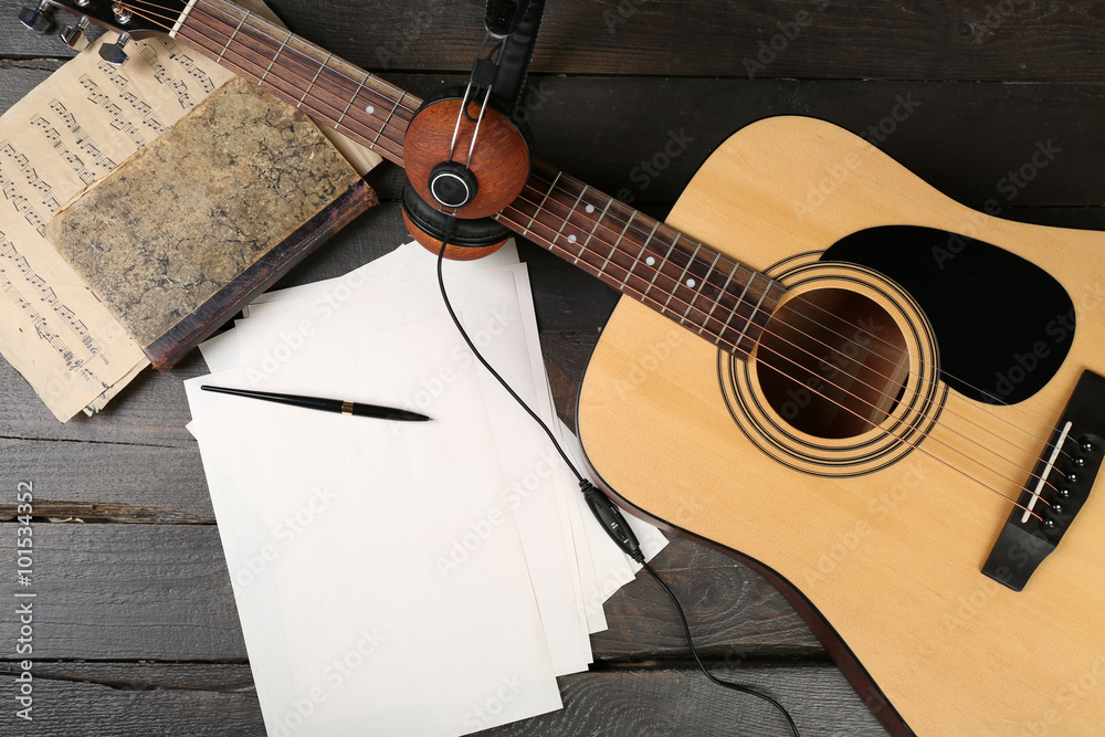 木背景的原声吉他、耳机、音符和白皮书，特写