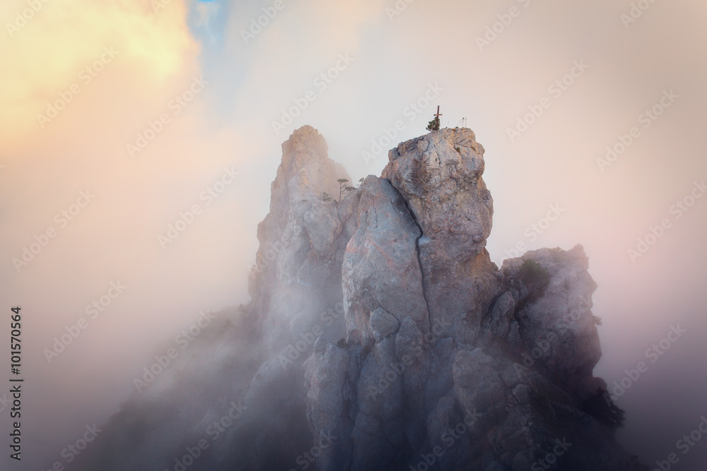 Top of the mountains. High rocks in fog at sunset. Colorful nature background