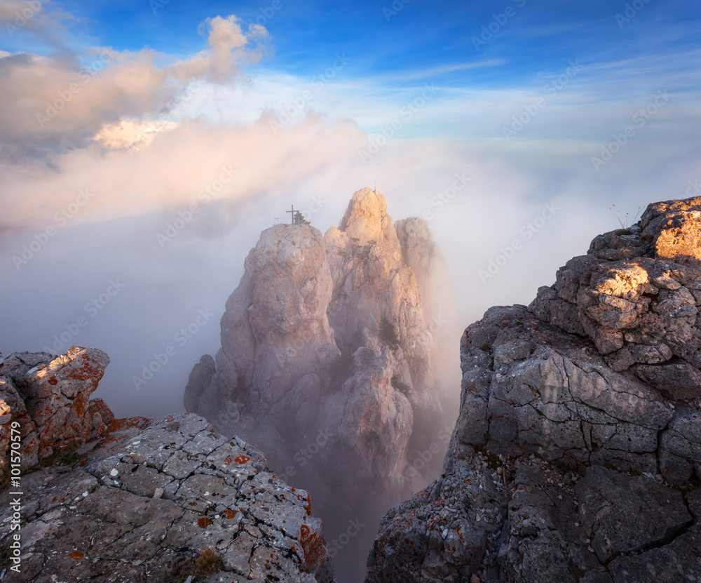 Top of the mountains. High rocks with low clouds at sunset. Colorful nature background