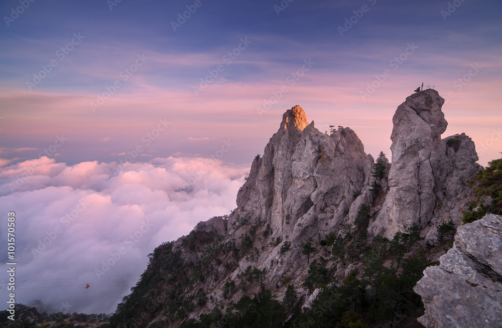 山顶。日落时高高的岩石和低云。多彩的自然背景