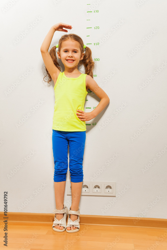 可爱女孩用手在墙上检查高度