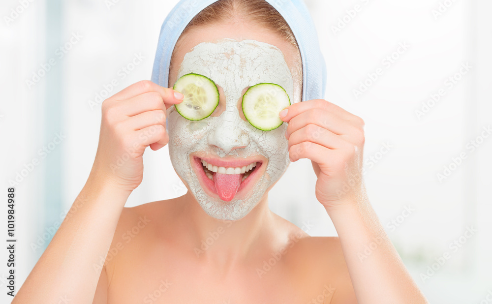 戴着皮肤脸和黄瓜口罩的有趣年轻女孩