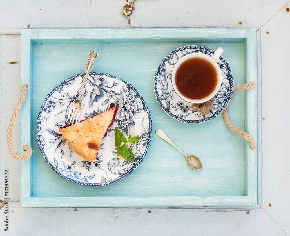 一块双层李子派和红茶，装在复古瓷杯里，蓝色木托盘。俯视图，h