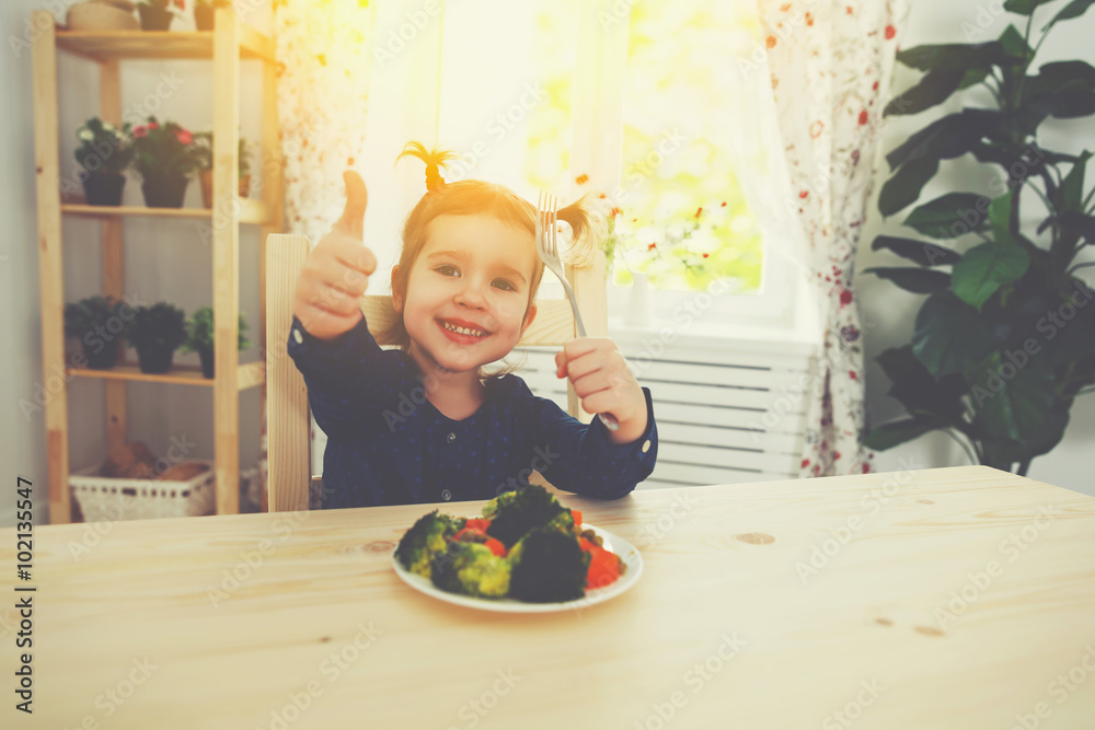 快乐的小女孩喜欢吃蔬菜并竖起大拇指