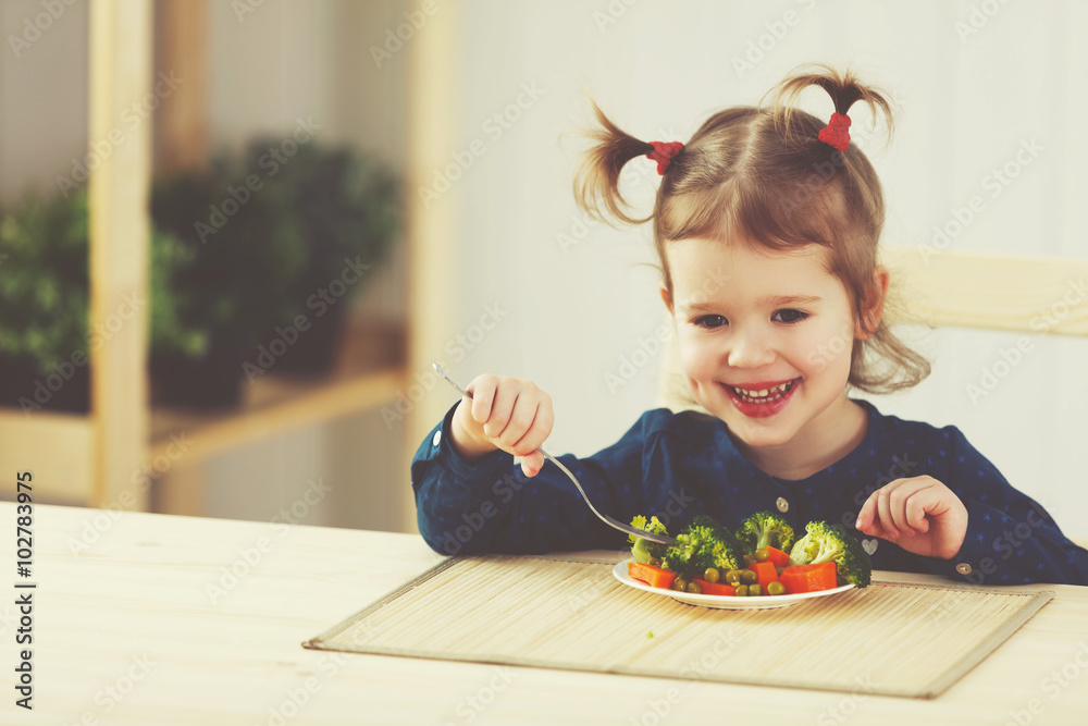 快乐的小女孩吃着蔬菜笑着