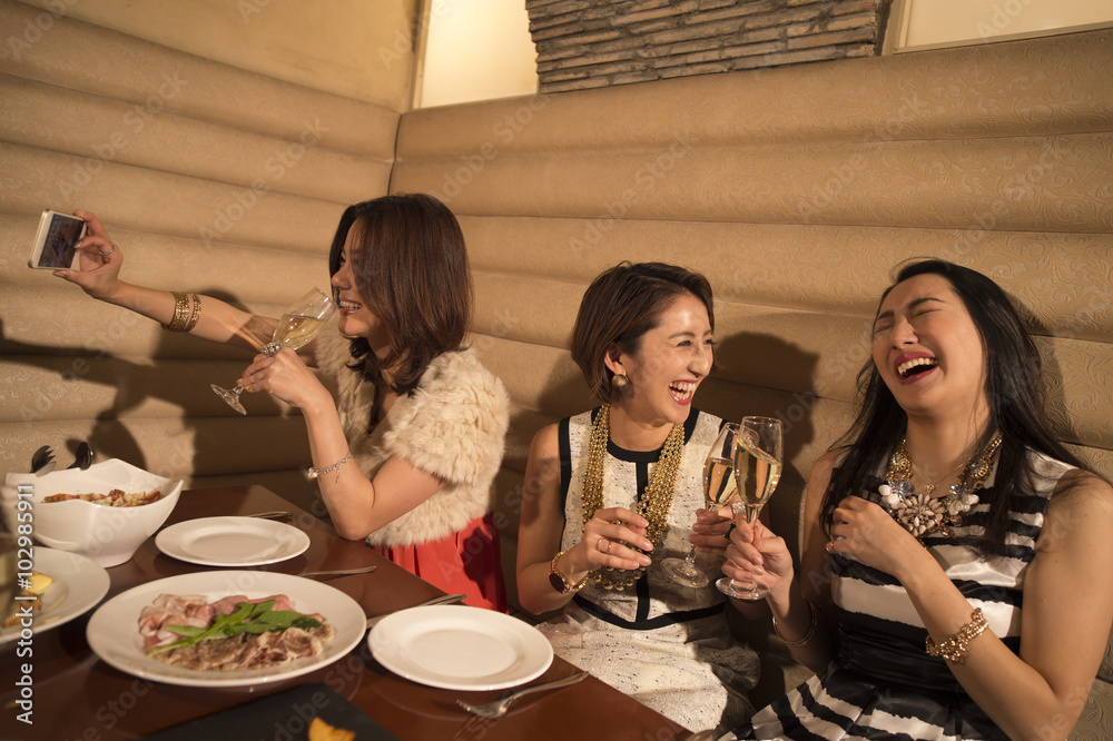 这些女性在餐厅用餐时使用了智能手机