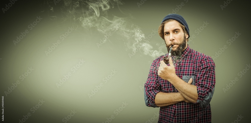 Composite image of hipster wearing knitted hat smoking pipe