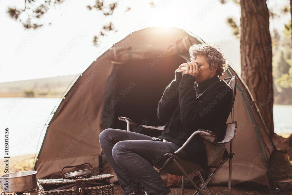 成熟的女人在露营地喝咖啡