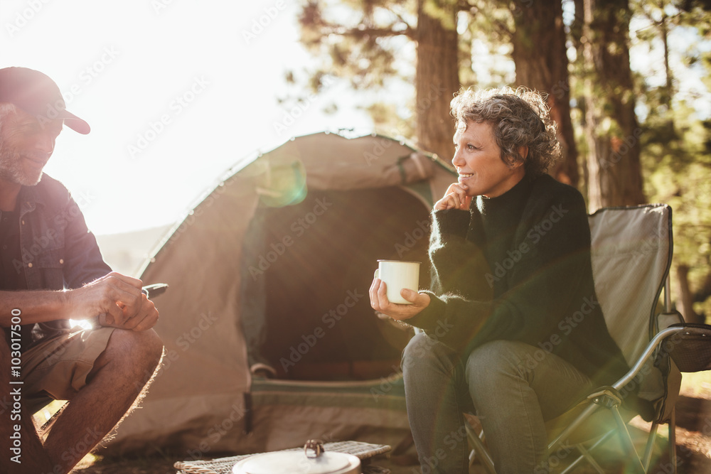 一对悠闲的夫妇坐在帐篷外，在湖边露营