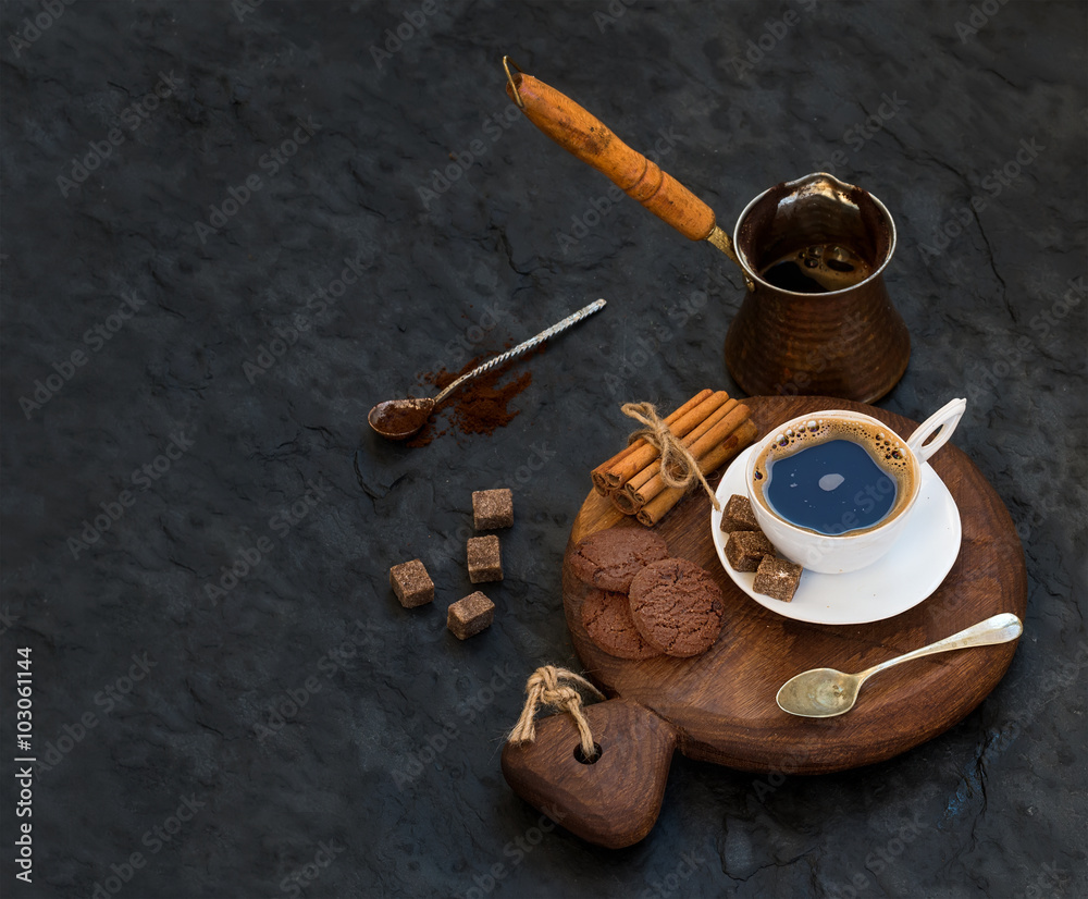 一杯黑咖啡，配巧克力饼干、肉桂棒和甘蔗糖块，放在乡村的木头b上