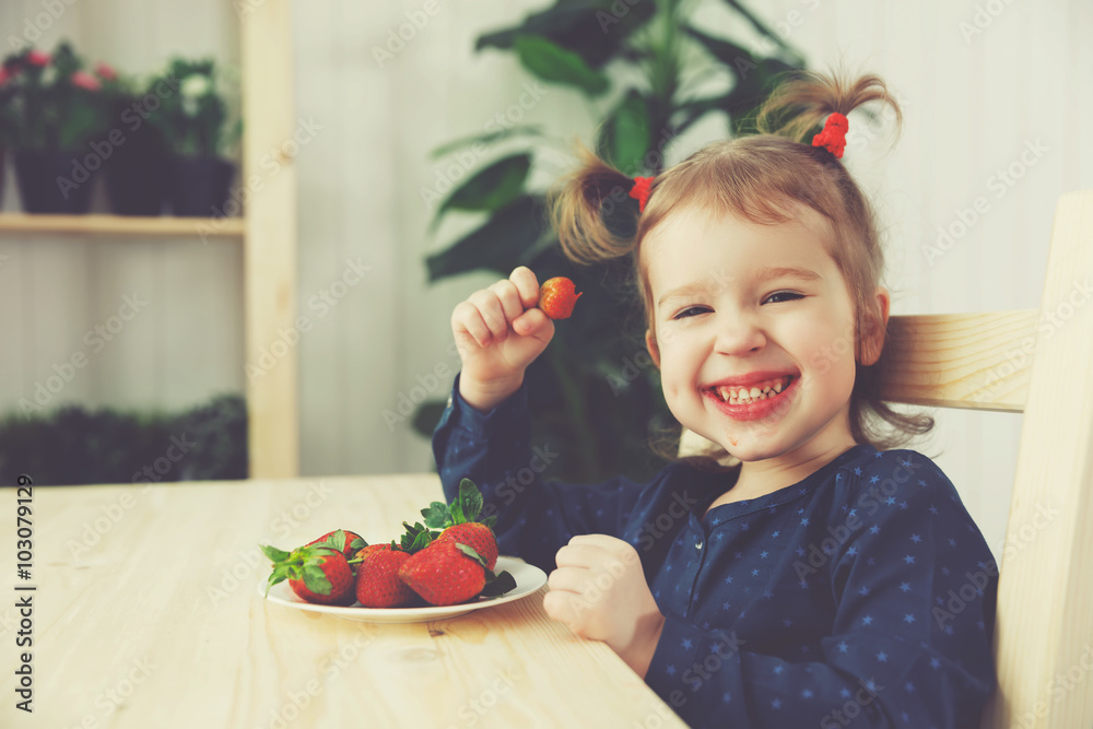 快乐的小女孩在夏日家庭厨房吃草莓