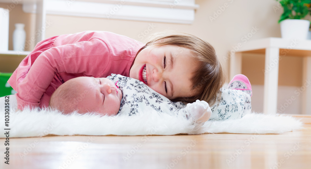 Happy toddler girl playing with her baby sibling