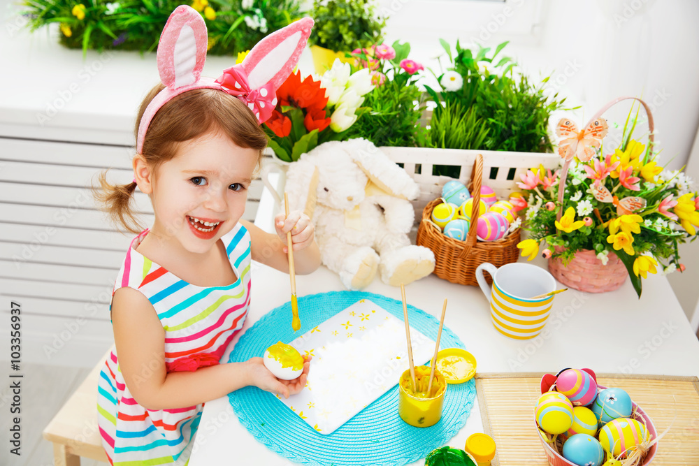  Happy child girl paints eggs for Easter