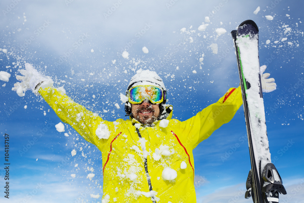 Happy skier man throw snow over sky