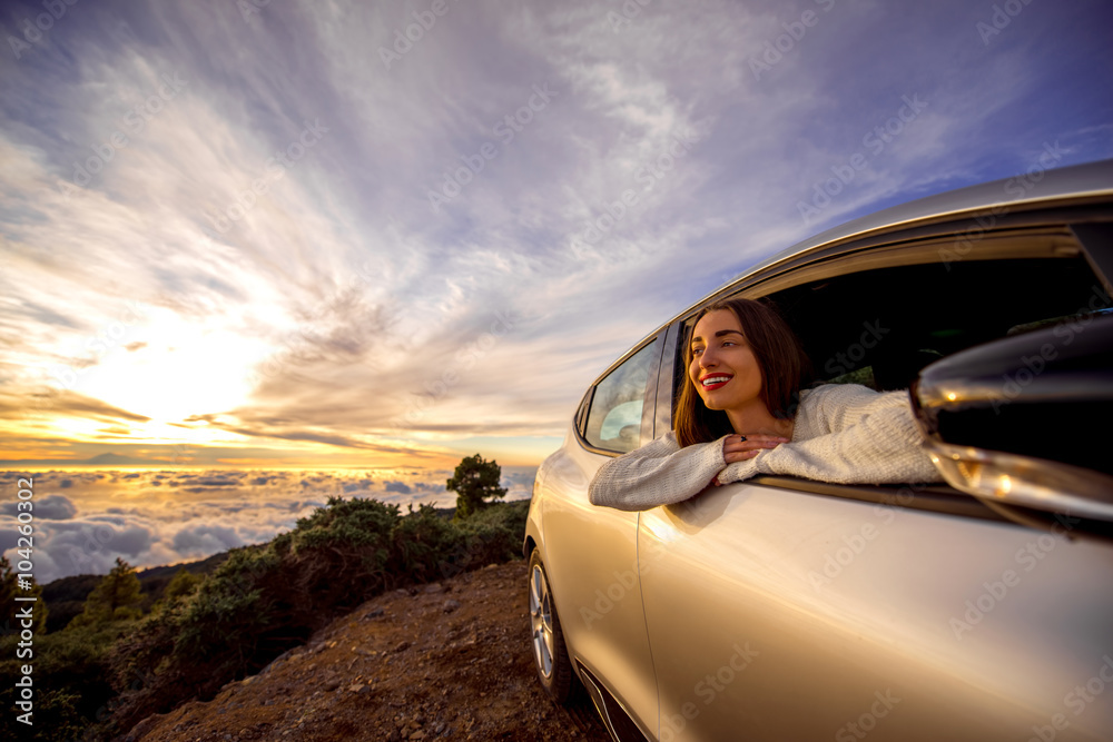 日出时，一位年轻女子从路边的车窗望出去，在云层上方。旅行愉快