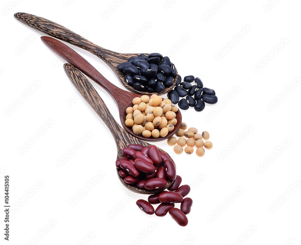 Red beans, soy beans, black beans, a wooden spoon on a white bac