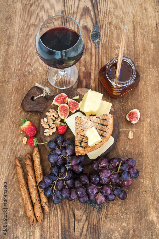一杯红酒、奶酪板、葡萄、无花果、草莓、蜂蜜和乡村木面包棒