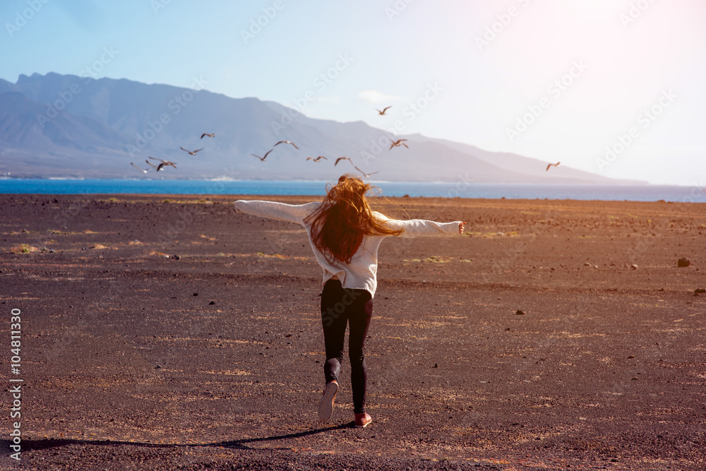 无忧无虑的女人跑向大海和山脉，Fue上的鸟在背景上飞翔