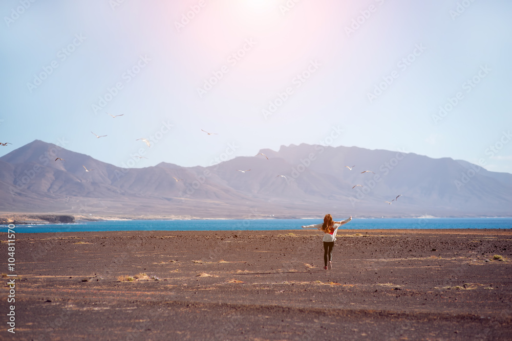 无忧无虑的女人跑向大海和山脉，Fue上的鸟在背景上飞翔