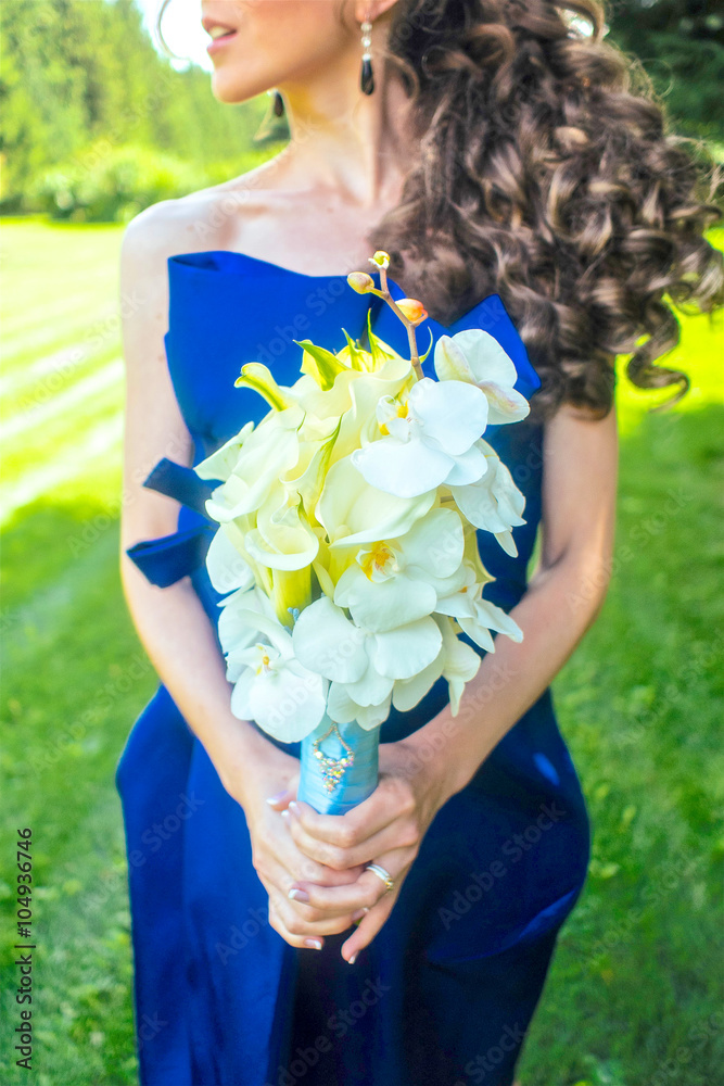 年轻卷曲的女人拿着一大束夏天的花