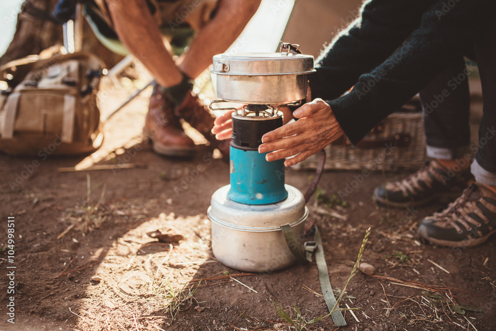 Woman camper warming her hands on camp stove
