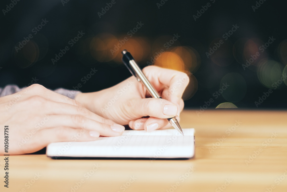 女孩晚上在木桌上写日记，特写