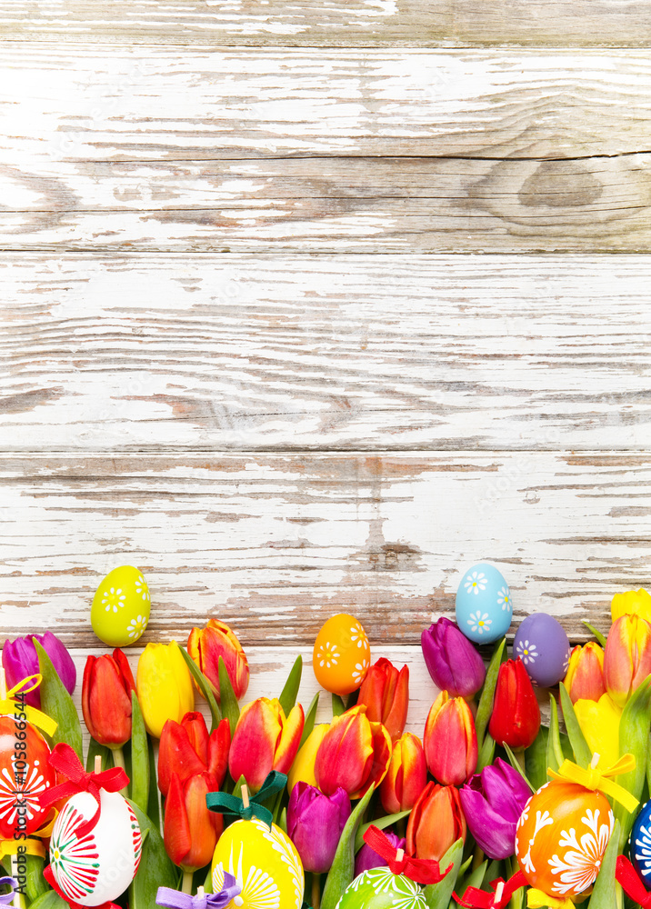 Easter eggs and tulips on wooden background