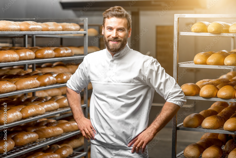 背景是面包和烤箱的面包店英俊面包师的肖像