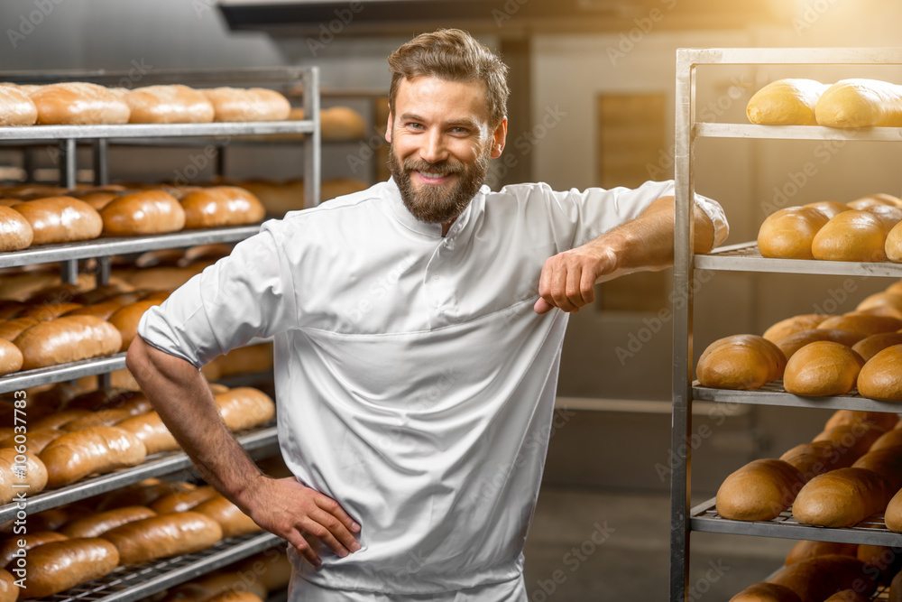背景是面包和烤箱的面包店英俊面包师的肖像