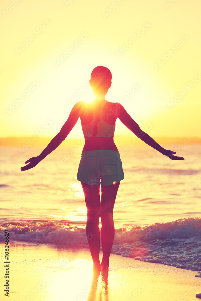 正念女性在海滩日出时练习瑜伽太阳礼。健康人的剪影