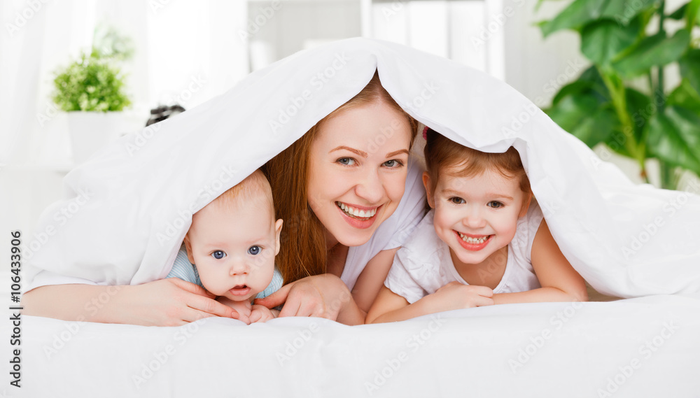 幸福的家庭母亲和两个孩子，儿子和女儿躺在床上