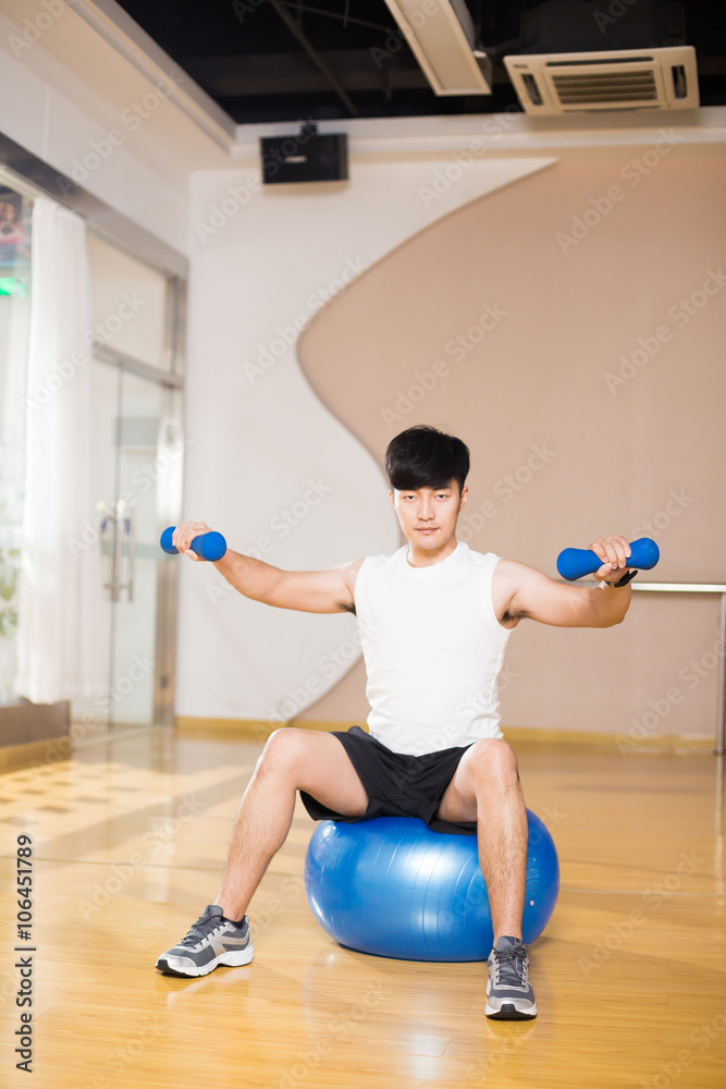 年轻英俊的亚洲男子在现代健身房锻炼